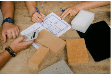 mains touchant des plans de maison avec des materiaux isolants